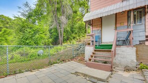 Een huis met een veranda, een trap naar de ingang en een omheinde tuin.