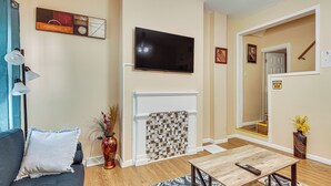Een woonkamer met een bank, een televisie, een open haard en een tafel.