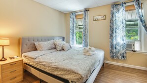 Een netjes opgemaakte slaapkamer met een bed, nachtkastje en een raam met gordijnen.