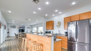 Une cuisine moderne avec des meubles en bois, des appareils en acier inoxydable et un îlot central doté de tabourets.