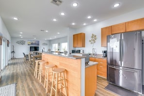 Een moderne keuken met houten kastjes, roestvrijstalen apparatuur en een centraal eiland met krukken.