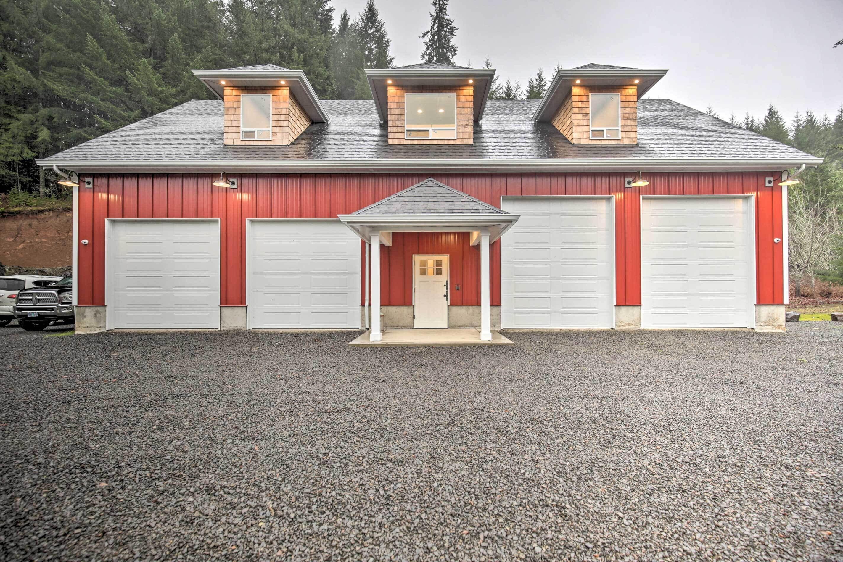 Ein zweistöckiges Gebäude mit roter Fassade, zwei Garagentoren und einem kleinen Vorbau mit einer Tür.