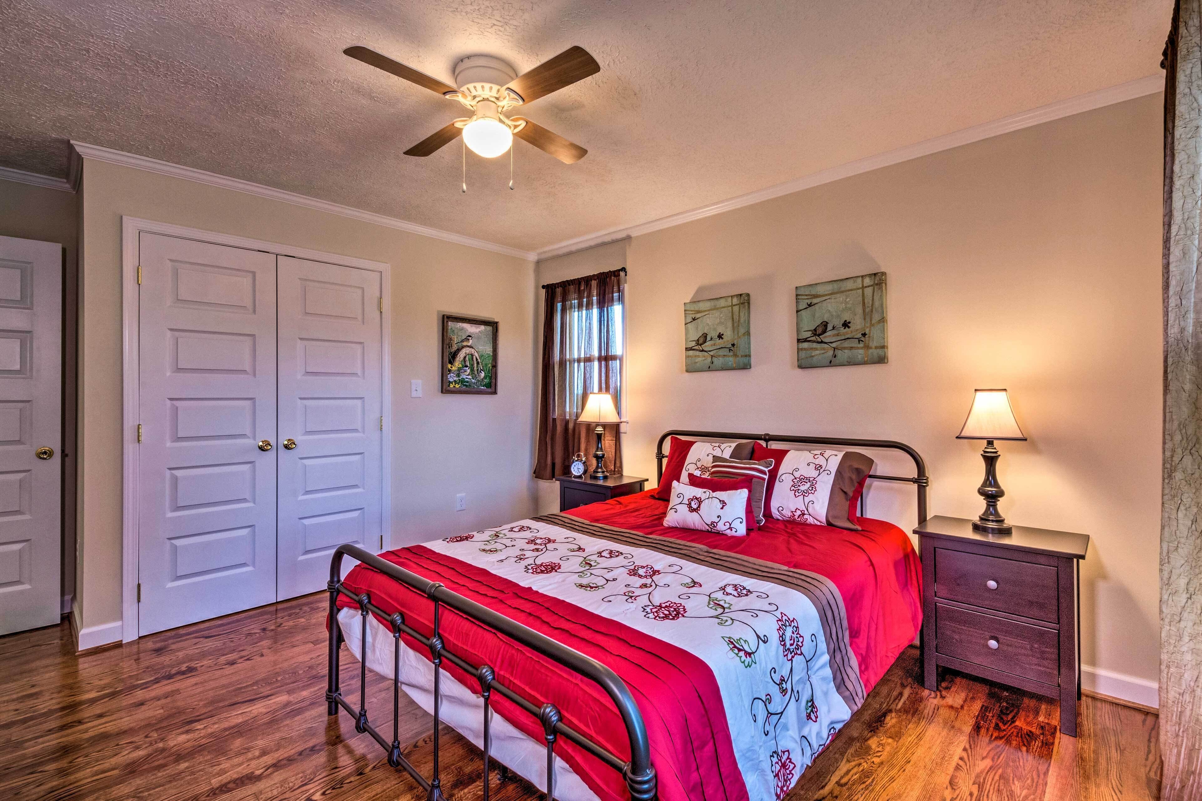 A bedroom with a bed, two bedside tables, a ceiling fan, and a window with curtains.