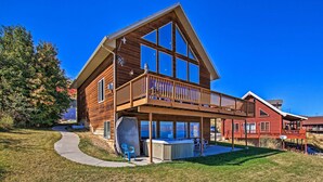 A two-story wooden house with a balcony, a hot tub, and a covered patio area. - Garden City Lake House: Hot Tub & Views! (Garden City)