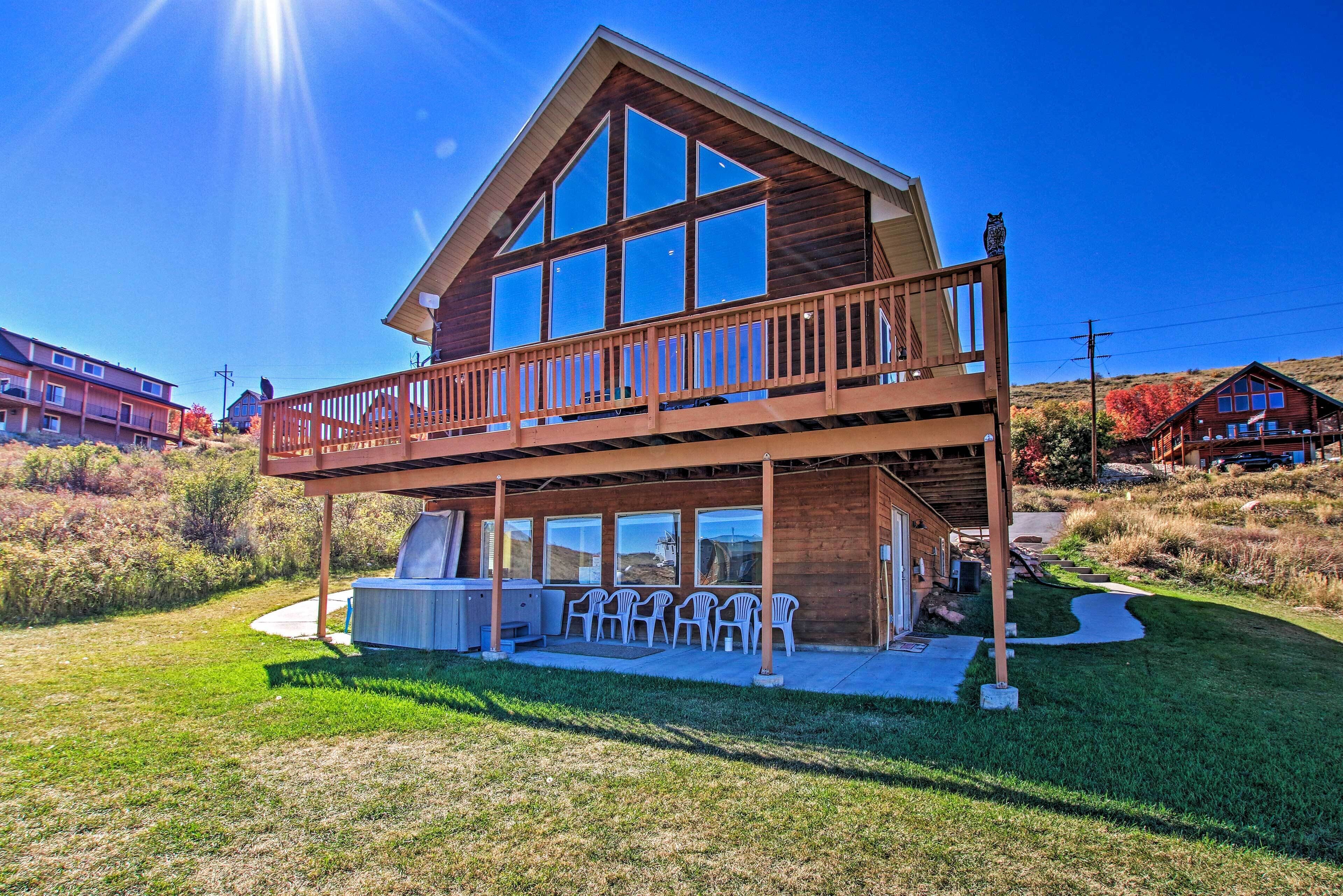 A two-story wooden house with a balcony, a barbecue area, and several chairs.