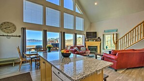 A spacious living area with a kitchen island, large windows, and a fireplace. - Garden City Lake House: Hot Tub & Views! (Garden City)