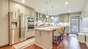 A modern kitchen with stainless steel appliances, a central island with bar stools, and pendant lighting. - 2 Mi to Duke & Dtwn Durham: Modern Home w/ Patio! (Durham)
