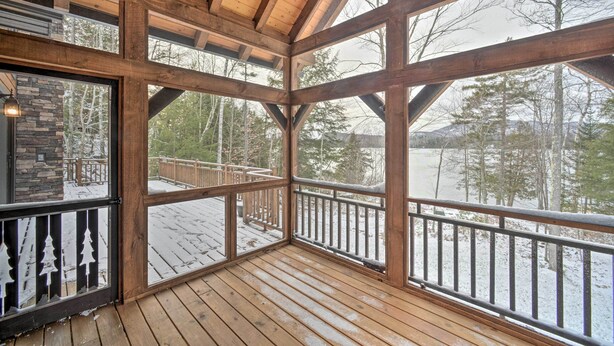 Una terraza de madera con vistas a un paisaje nevado y árboles.