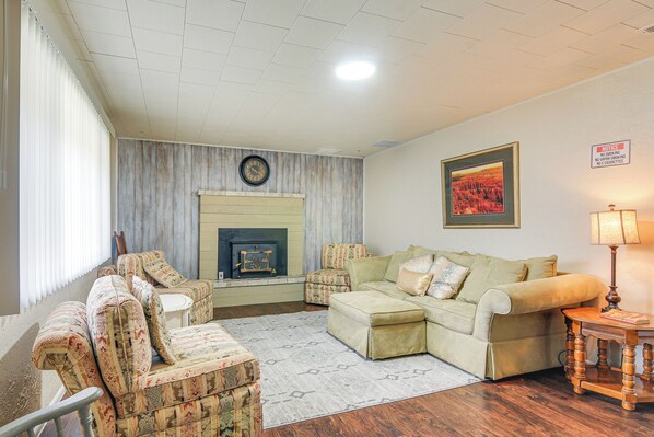 A living room with a fireplace, patterned armchairs, a sofa, and a lamp.