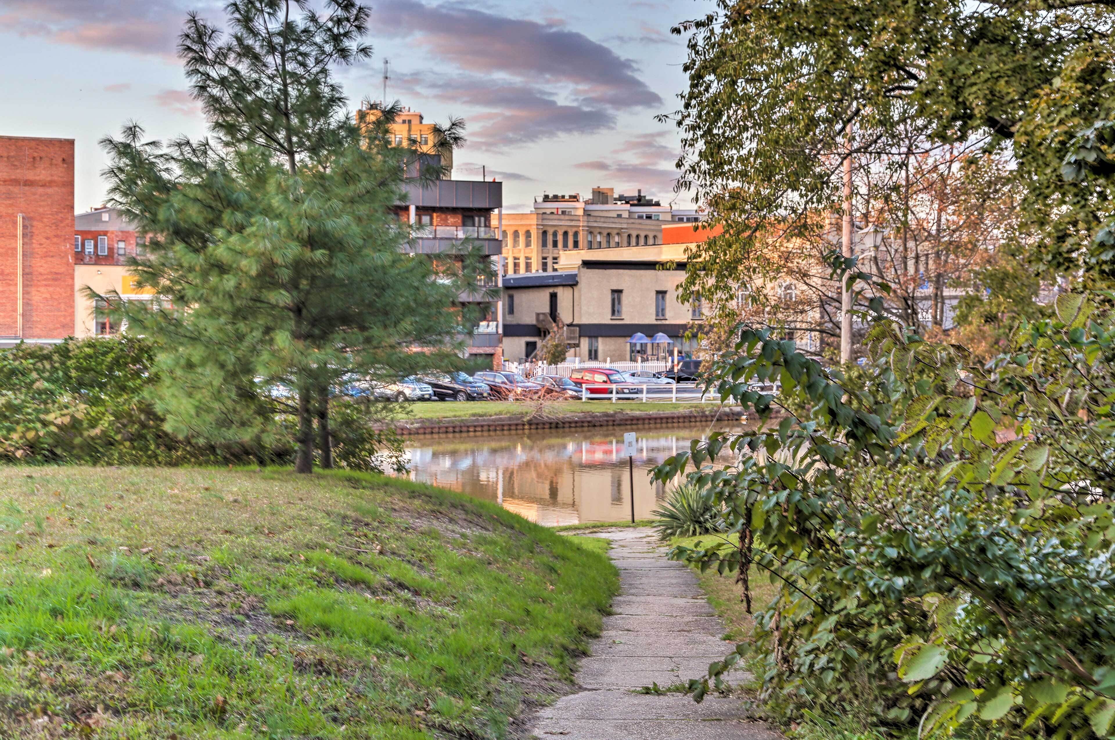 A pathway leading to a body of water with buildings in the background.
