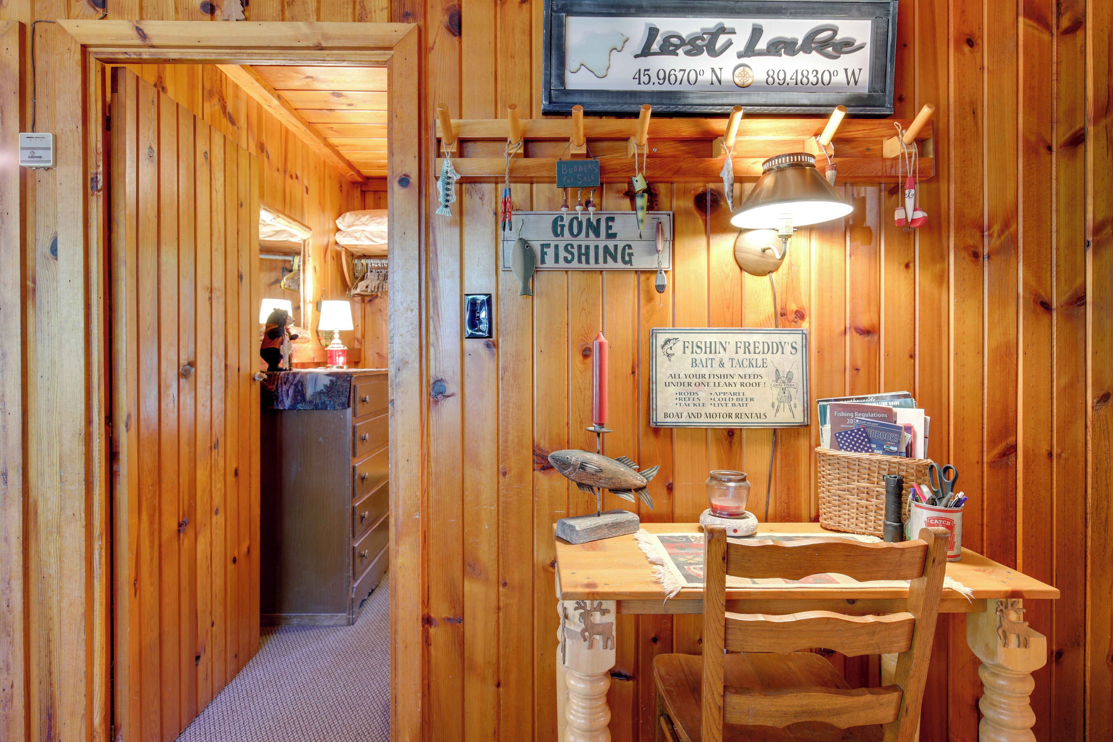 A wooden interior with a sign reading "Gone Fishing" and a table with fishing-related items.