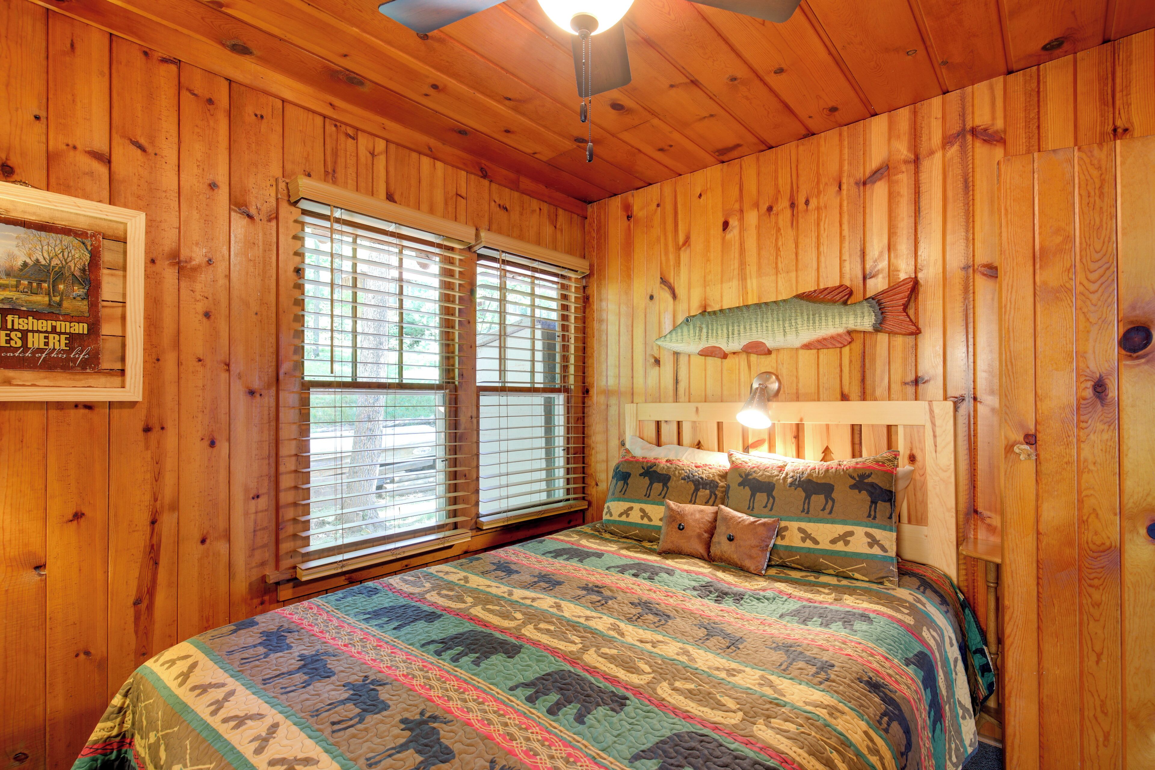 Ein Schlafzimmer einer Holzhütte mit einem Bett, einer Fischdekoration an der Wand und einem gerahmten Bild.