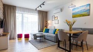 A modern living room with a sofa, a dining table with chairs, a coffee table, and a fireplace. - RentPlanet - Stone Hill (Szklarska Poreba)