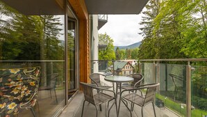 A balcony with a glass door, wicker chairs, and a table. - RentPlanet - Stone Hill (Szklarska Poreba)