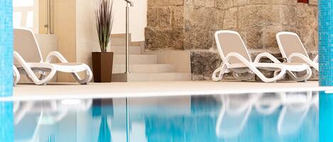 A swimming pool with two lounge chairs and a potted plant.