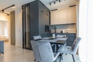 Una cocina moderna con comedor, que incluye una mesa grande y sillas tapizadas en gris.