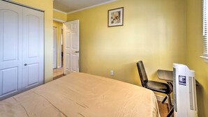 A bedroom with a bed, a chair, a white air conditioner, and a door leading to another room. - Inkster Home Near Airport & Henry Ford Museum (Inkster)