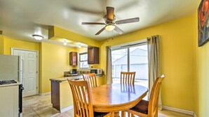 A dining area with a wooden table and chairs, a ceiling fan, and a kitchen in the background. - Inkster Home Near Airport & Henry Ford Museum (Inkster)