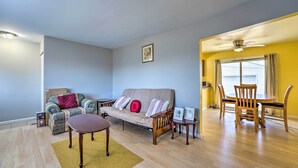 A living room with a sofa, a coffee table, a dining table with chairs, wooden flooring, and a ceiling fan. - Inkster Home Near Airport & Henry Ford Museum (Inkster)