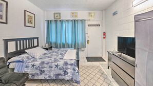 Une chambre à coucher avec un lit, une télévision, une commode et une porte sur laquelle est apposée une pancarte.