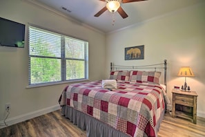 A bedroom with a bed, a nightstand, a lamp, a ceiling fan, a window with blinds, and a wall-mounted TV. - Townsend Condo w/ Pool, Great Smoky Mountain Views (Townsend)