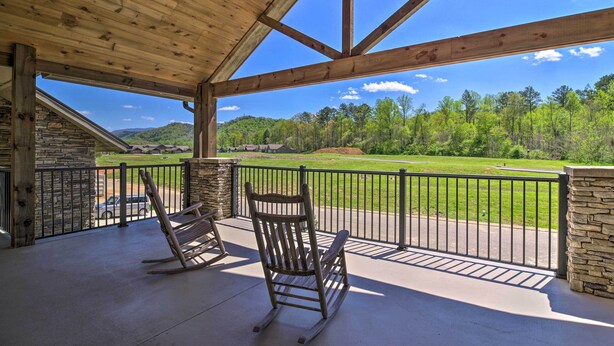 A covered porch with two rocking chairs, a stone wall, and a view of a green landscape and mountains. - Townsend Condo w/ Pool, Great Smoky Mountain Views (Townsend)