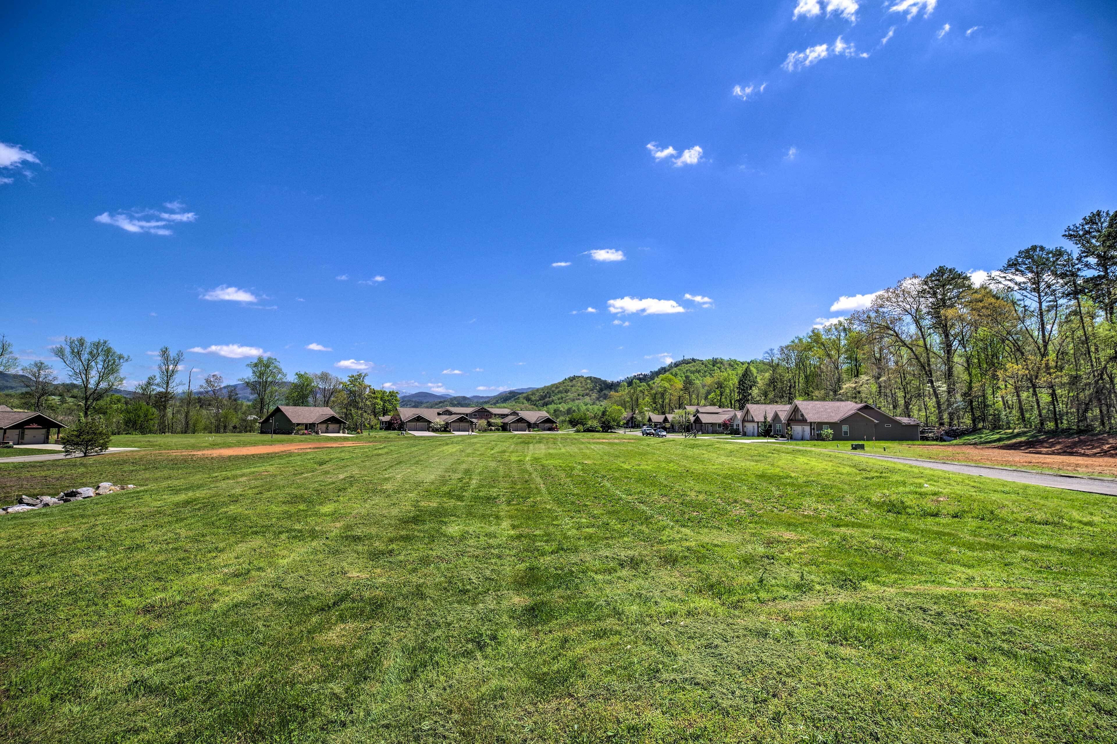 A grassy field with several wooden cabins and a clear blue sky.