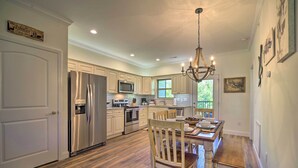 A spacious kitchen with white cabinetry, stainless steel appliances, and a wooden dining table. - Townsend Condo w/ Pool, Great Smoky Mountain Views (Townsend)
