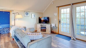 A living room with a sofa, television, fireplace, and large windows. - Near Douglas Lake: Mountain Jewel Haven w/ Views (Sevierville)