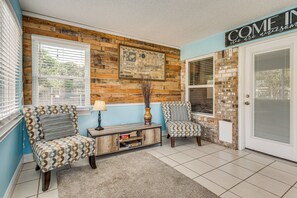 A room with two patterned armchairs, a wooden console table, and a decorative wall with a 'COME IN' sign. - Welcoming Pensacola Home w/ Spacious Yard! (Pensacola)