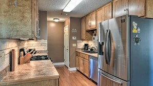 A modern kitchen with wooden cabinets, stainless steel appliances, and a granite countertop.