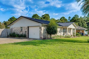 Une maison à deux étages avec un garage, une véranda et une pelouse bien entretenue.