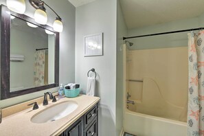 Un baño con lavabo, espejo y ducha.