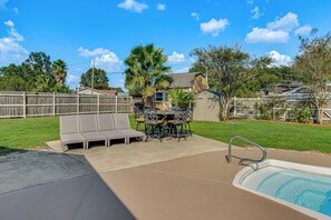 Ein Garten mit Schwimmbad, überdachter Terrasse und Holzumzäunung.