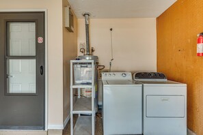 Ein Waschraum mit Waschmaschine und Trockner, einem Warmwasserbereiter und einer Tür mit Rauchverbot-Hinweis.
