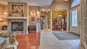 A spacious living room with a fireplace, a dining area with wooden furniture, and a large window with decorative glass. - Elegant Valrico Home ~ 15 Mi to Downtown Tampa! (Valrico)