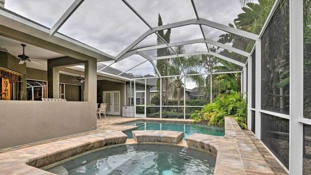 A covered outdoor swimming pool area with a glass ceiling, stone steps, and surrounding greenery. - Elegant Valrico Home ~ 15 Mi to Downtown Tampa! (Valrico)