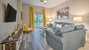 A modern living room with a grey sofa, yellow chair, and a flat-screen TV mounted on the wall. - Resort Condo w/ Patio + Pool Access in Davenport! (Davenport)
