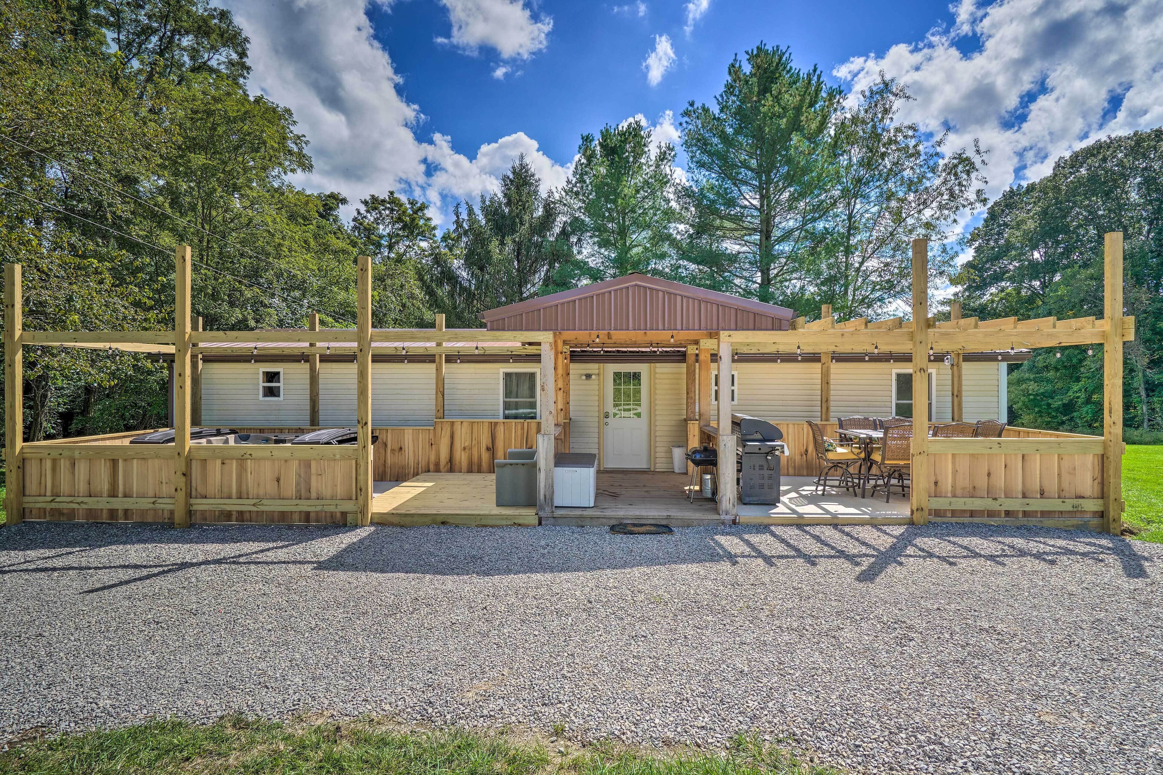 Une cabane en bois dotée d’un patio couvert, d’un espace barbecue et d’une allée en gravier.