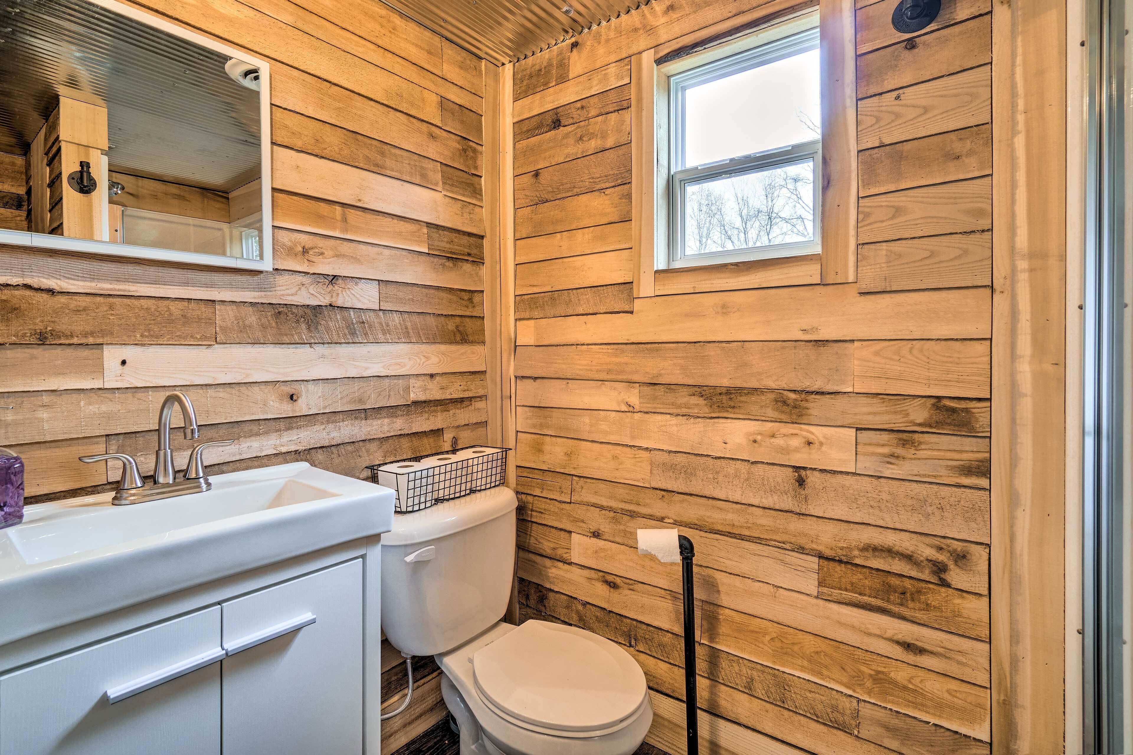 A compact bathroom with wooden walls, a white sink, and a toilet.