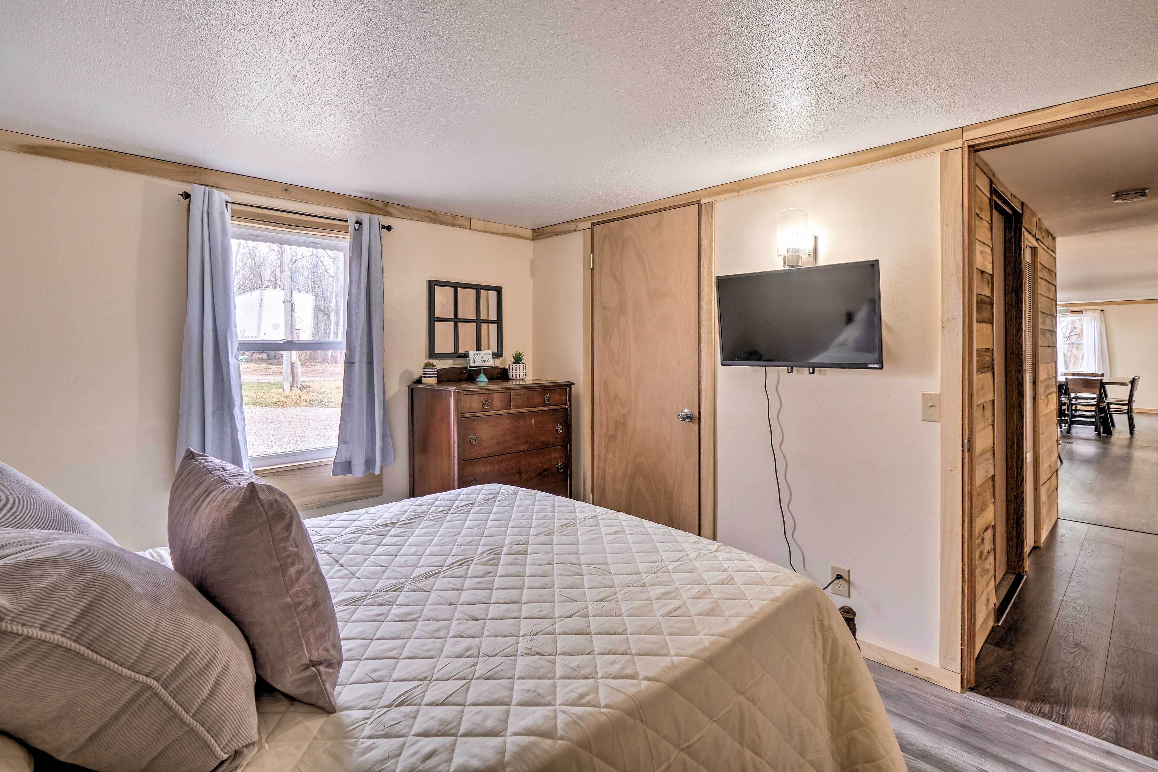 Un dormitorio con cama, cómoda, televisor y puerta corredera que da a otra habitación.