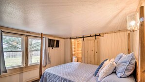 A bedroom with a large bed, wooden walls, and a window with curtains. - 'take 5' Retreat w/ Hot Tub: Relax, Rest, Refresh! (Somerset)