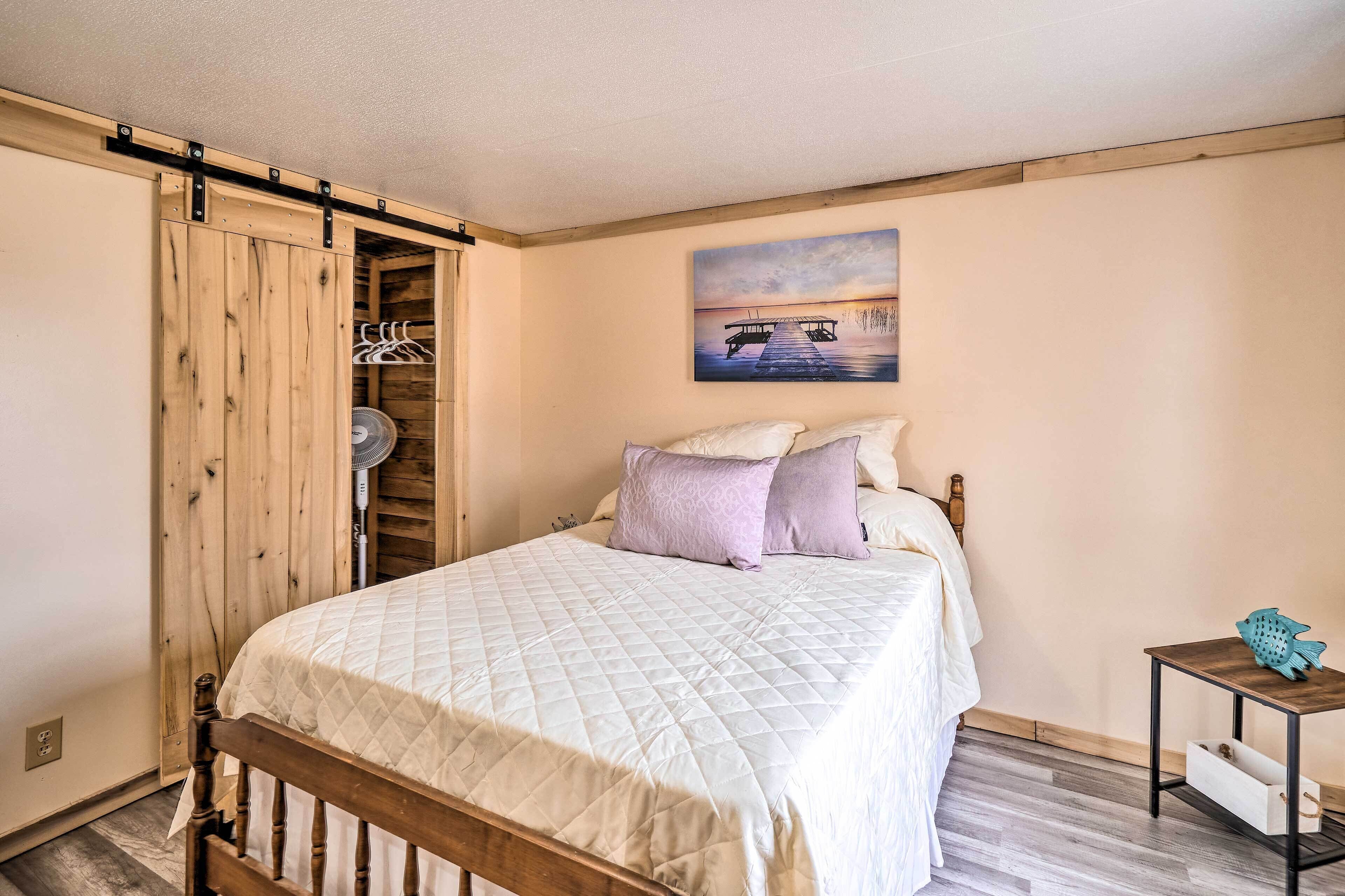 Ein Schlafzimmer mit einem Bett, einem Holzschrank, einem Gemälde und einem kleinen Tisch mit Fischdeko.