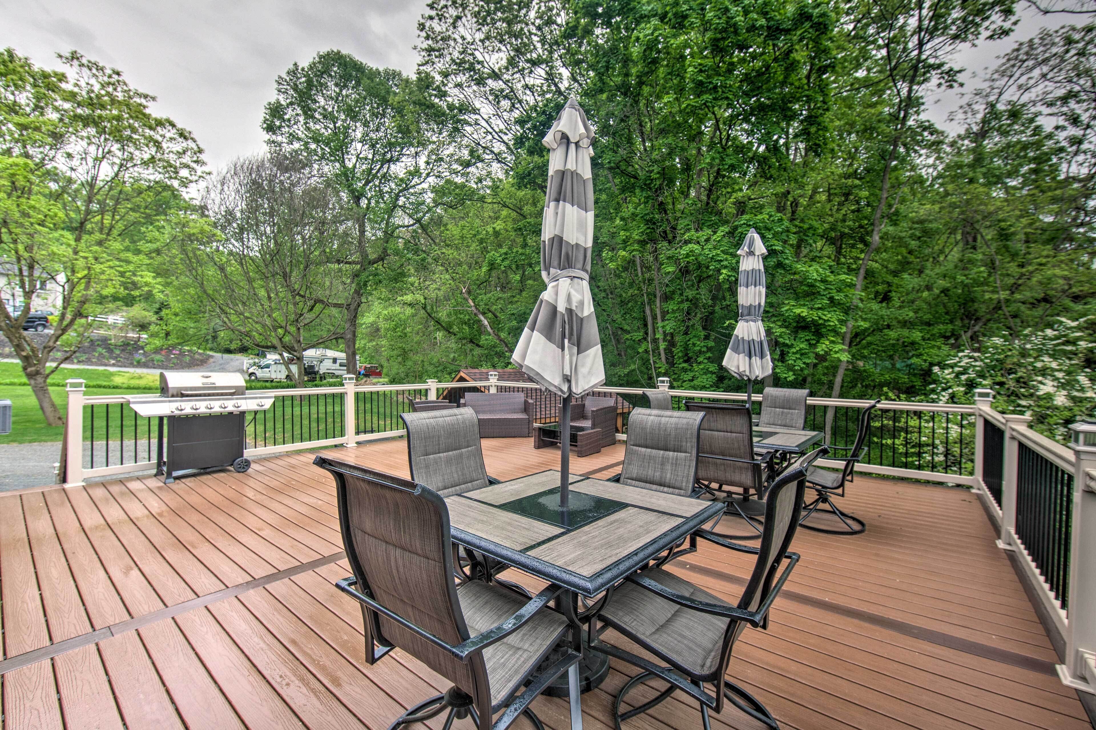 An outdoor deck with a grill, seating area, and umbrellas.