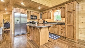 A wooden cabin-style kitchen with a central island, built-in appliances, and a large window. - Lake View & Hot Tub: Wrightsville Cabin! (Wrightsville)