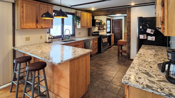 A spacious kitchen with a large island, wooden cabinets, and a granite countertop. - Burlington Flats House < 13 Mi to Cooperstown! (Burlington Flats)