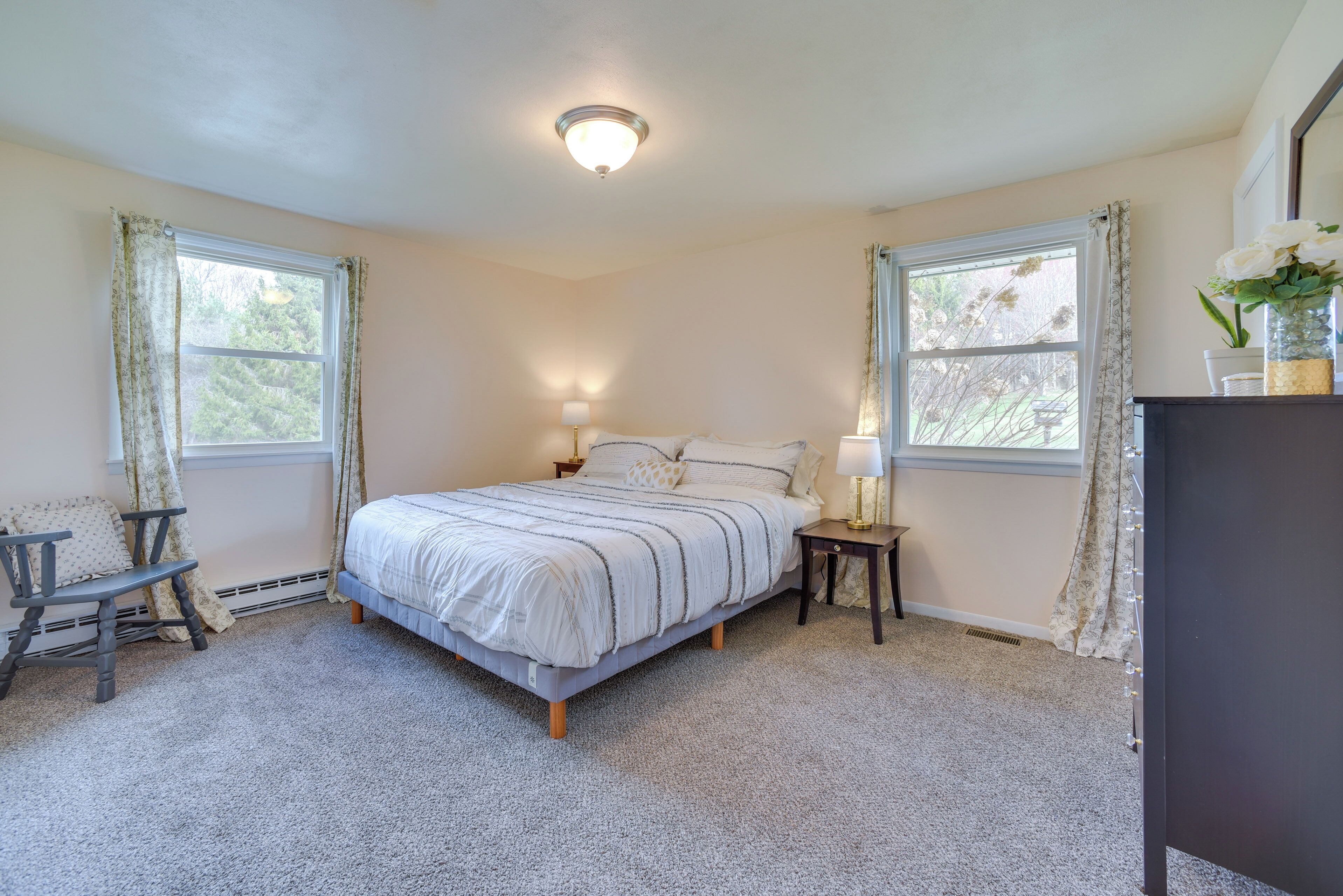 Une chambre à coucher comprenant un lit, deux tables de chevet, une chaise et une commode.