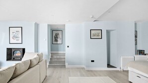 Ein modernes Schlafzimmer mit einem Bett, einer Couch, einem Kamin und gerahmten Kunstwerken an den Wänden.