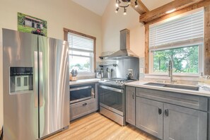 A modern kitchen with stainless steel appliances, wooden flooring, and large windows. - Historic Charm + Modern Luxury: 6 Mi to Stowe Mtn (Stowe)