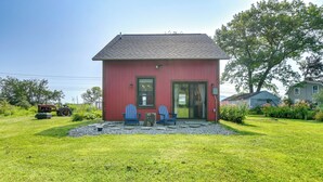 Ein kleines rotes Haus mit einer Veranda, zwei blauen Stühlen und einem Holztisch.